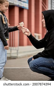 Maniac Kidnapper With Evil Face Offering Lollipop To Child Girl On City Street. Adult Man Giving Lollies To Little Kid. Concept Of Pedophilia And Kidnapping Danger To Children Left Alone.side View