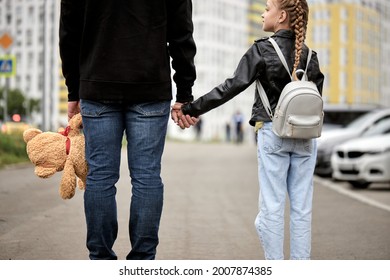 Maniac man holds the hand of teenage girl in street. The concept of kidnapping and child trafficking. View from back on pedophile and caucasian child girl walking along the street. Crime, violence