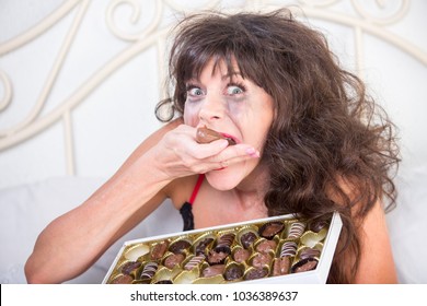 Manic Mature Woman Crying And Eating Chocolates In Her Bedroom