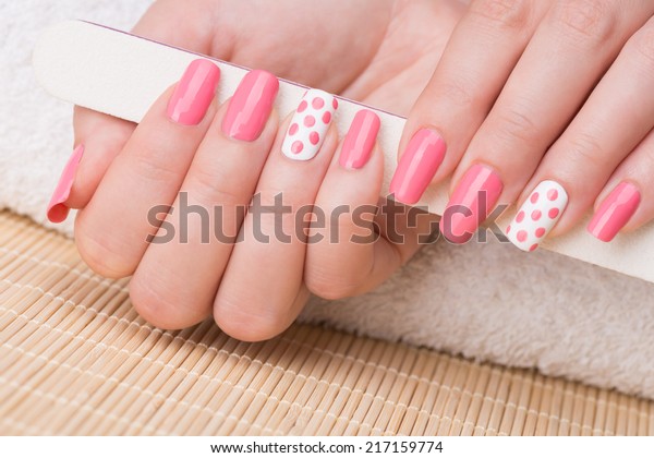 マニキュア 美しいマニキュアを施した女性の爪を持つ爪ファイルの美容写真 ピンクと白のマニキュアを美しく輝かせた女性のネイルアート の写真素材 今すぐ編集