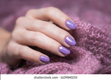 Manicure Female Hand Isolated At Soft Fluffy Knitted Background. Fingernails With Purple Painted Nails Decorated With Drawn White Cute Small Hearts.