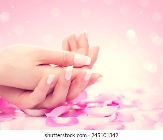 Manicure, Hands spa Beautiful feamle hands, soft skin, beautiful nails with pink rose flowers petals. Healthy Woman hands. Beauty salon. Beauty treatment. Beautiful nails with french manicure 