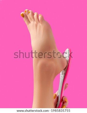 Manicure, pedicure beauty salon concept. Womans leg with foot grater on pink background