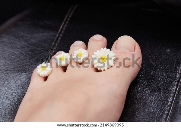 A manicure and pedicure master puts\
dividers on his fingers in a pedicure salon. Dividers for pedicure\
in the form of flowers. Black gloves on his hands.\
