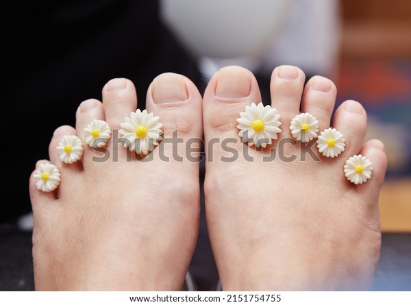A manicure and\
pedicure master puts dividers on his fingers in a pedicure salon.\
Dividers for pedicure in the form of flowers. Black gloves on his\
hands. Foot care procedure, 