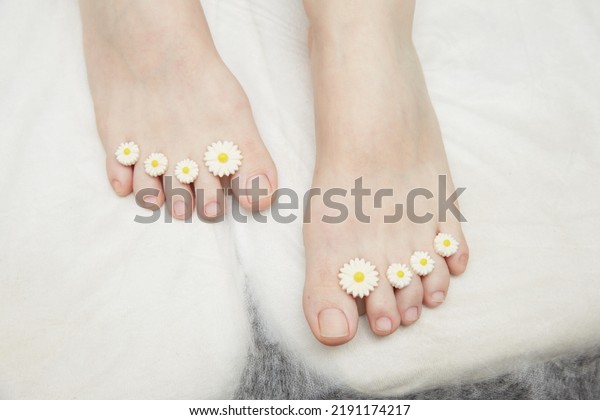 A manicure and
pedicure master puts dividers on his fingers in a pedicure salon.
Dividers for pedicure in the form of flowers. Black gloves on his
hands. Foot care procedure