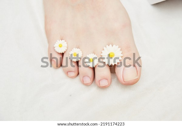 A manicure and\
pedicure master puts dividers on his fingers in a pedicure salon.\
Dividers for pedicure in the form of flowers. Black gloves on his\
hands. Foot care procedure