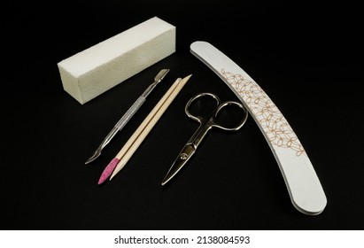 Manicure And Pedicure Tools On Black Background. Silver Scissors, Nail File, Buffer Block, Cuticle Pusher And Orange Wood Sticks.