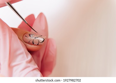 Manicure process. The master draws a butterfly drawing on the fingernail with a thin brush. - Shutterstock ID 1927982702