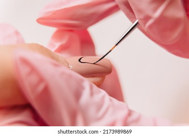 Manicure Process. A Master Manicurist Makes A Drawing On Artificial Nails Using Black Varnish And A Thin Brush.