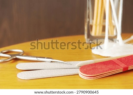 Manicure set with nail files, scissors, and cotton swabs on a wooden table. Professional grooming and self-care tools for spa and beauty themes