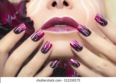 Manicure and white wavy lines black rhinestones   smooth transition from dark maroon to bright colors nail Polish square shape   gladiolus in female hand 