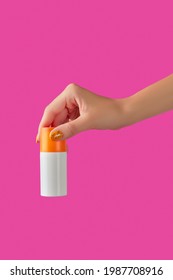 Manicured Womans Hand Holding Sunscreen Bottle On Pink Background