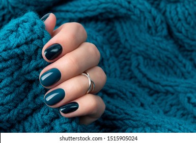 Manicured woman's hand in warm wool turquoise sweater. Fashionable autumn winter nail design. 