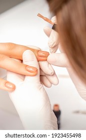 Maniküre, die beige Nagellack auf die Fingernägel eines weiblichen Klienten in einem Nagelsalon aufträgt