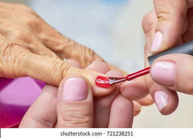 Manicurist Applying Red Varnish To Senior Woman. Nails Beautician Painting Nails To Old Woman In Beauty Salon.