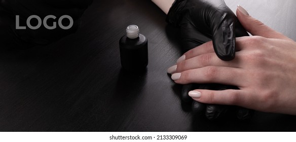 Manicurist In Black Gloves Paint The Girl's Nails With Varnish. Do A Manicure In The Salon, The Development Of Your Business. Close-up Of A Drop On A Brush