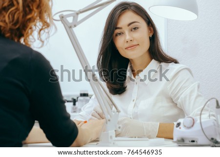 Manicurist does manicure for client