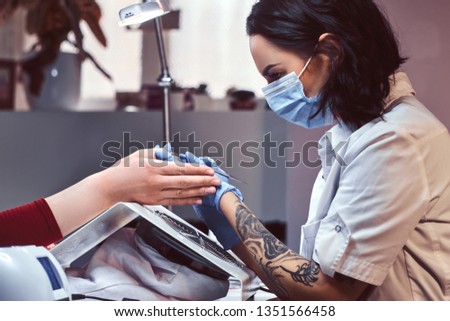The manicurist does the procedure to trim and remove cuticles in the beauty salon