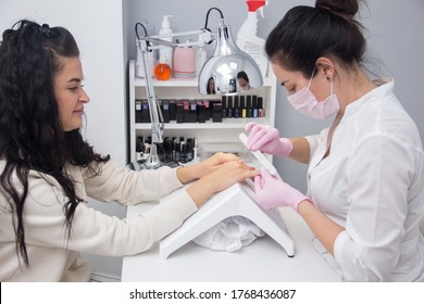 A Manicurist Gives A Manicure To A Client. Portrait Of An Attractive Nail Salon Worker Giving A Manicure To One Of Her Regular Customers