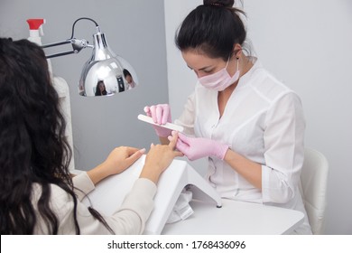 A Manicurist Gives A Manicure To A Client. Portrait Of An Attractive Nail Salon Worker Giving A Manicure To One Of Her Regular Customers