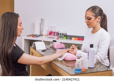 A Manicurist Giving A Manicure To A Client. Portrait Of An Attractive Nail Salon Worker Giving A Manicure To One Of Her Regular Clients. High Quality Photo