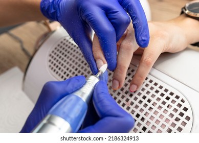 The Manicurist Grinds The Nail Plate With A Milling Machine In Blue Latex Gloves.