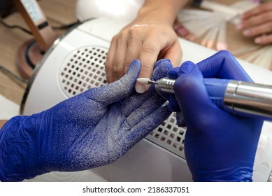 The Manicurist Grinds The Nail Plate With A Milling Machine In Blue Latex Gloves.