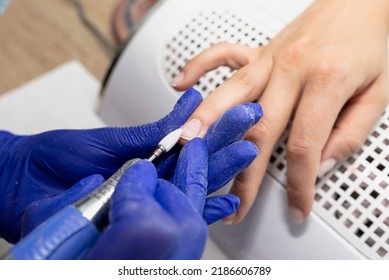 The Manicurist Grinds The Nail Plate With A Milling Machine In Blue Latex Gloves.