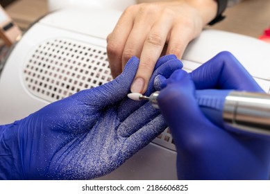 The Manicurist Grinds The Nail Plate With A Milling Machine In Blue Latex Gloves.