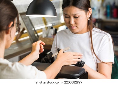 Manicurist Processes Nails Of A Client With A Nail File In A Beauty Salon. Asian Appearance