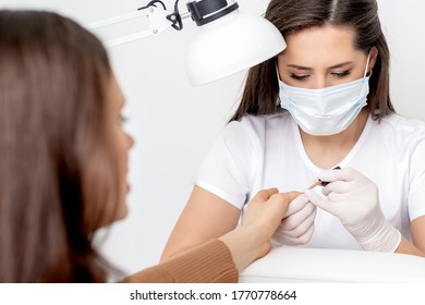 Manicurist In Protective Mask Painting Female Nails With Nail Polish In Manicure Salon.