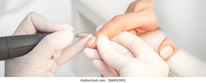 Manicurist removes nail polish uses the electric machine of the nail file during manicure - Powered by Shutterstock