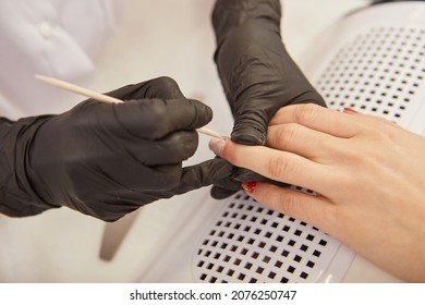 Manicurist Removing Cuticle On Woman Hand With Orange Wood Stick