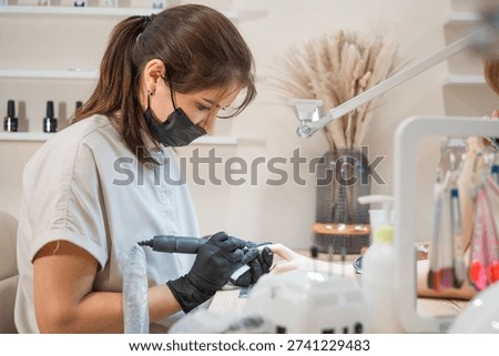 A manicurist sharpens nails with a drill machine during the procedure