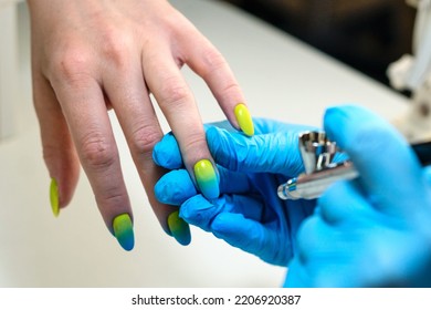 Manicurist using airbrush to paint fingernails female client in nail salon. Master does design nails with airbrush. Woman customer getting nail manicure. Process procedure for spraying paint on nails