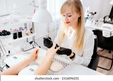 Manicurist work on a woman client hands, make her nails look beautiful. Salon procedure in process. Professional works in gloves for sterility - Powered by Shutterstock