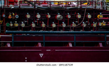 Manifolds and pipes on a large commercial cargo tanker ship moored at port.