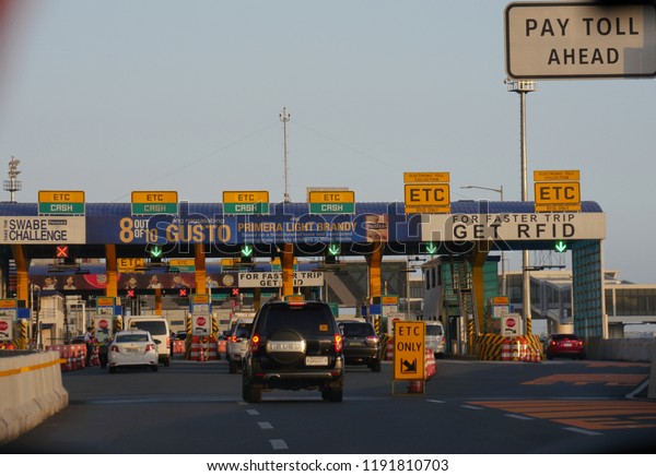 MANILA, PHILIPPINES—MARCH 2018: Vehicles\
stop to pay at a toll gate in Pasay City.\
