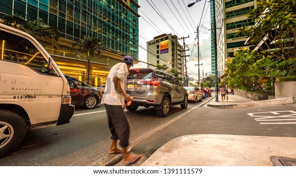 MANILA, PHILIPPINES - CIRCA\
MARCH 2018: View of traffic on the streets of the city as cars and\
pedestrians pass by during dusk circa March, 2018 in Manila,\
Philippines.