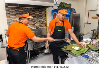 Manila, Philippines - July, 26, 2016: Two young men serving food in a filipino restaurant kitchen in Manila