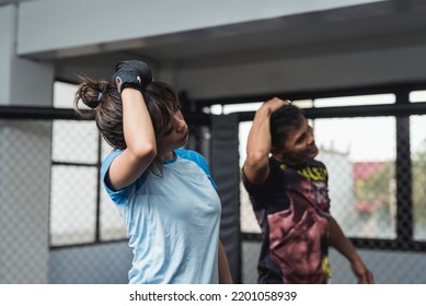 Manila, Philippines - June 2022: A Professional Muay Thai Fighter Teaches A Novice Student Warm Up Drills At An MMA Gym.