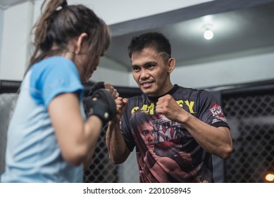 Manila, Philippines - June 2022: A Professional Muay Thai Fighter Teaches A Novice Student At An MMA Gym.