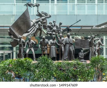 Manila, Philippines - March 5, 2019: Bronze Group Statue Of Exited People Around And On A Military Tank With A Victory Effigy Of Woman With Torch Stands Near Yuchenco Museum.