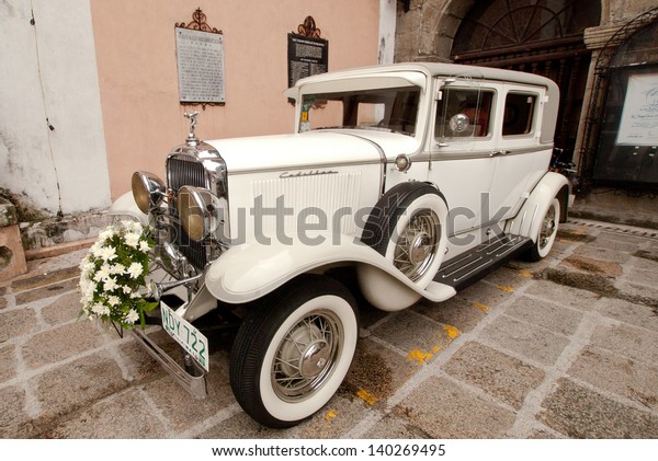 MANILA, PHILIPPINES -MAY\
6:A classic wedding car park in front of  San Agustine church\
during a wedding ceremony on May 6,2012  Intramuros district of\
Manila, Philippines.