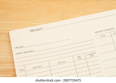 Manila project plan folder with task section on a wood desk