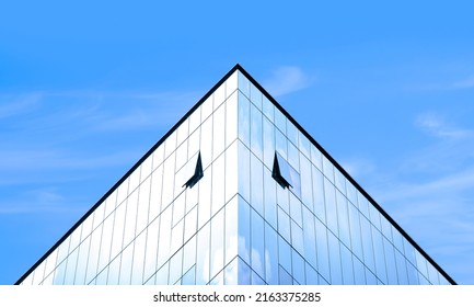 Manipulation techniques image of light reflection on surface of modern glass office building against blue sky background in symmetry and low angle view