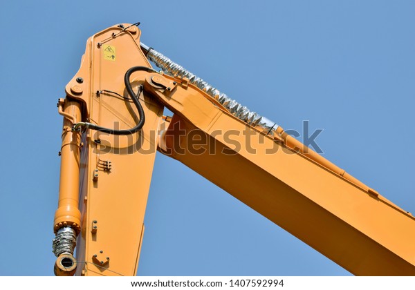 Manipulator crane with hydraulic cylinder. Working\
equipment of logging equipment. Close-up of the crane fragment.\
Against the blue\
sky.