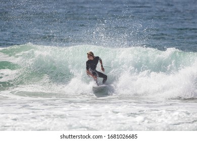 MANLY, NSW/AUSTRALIA – MARCH 2020: Young Adults Catching Waves Surfing At Manly Beach On A Bright Warm Sunny Day On Clear Blue Water