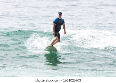 MANLY, NSW/AUSTRALIA – MARCH 2020: Young Adults Catching Waves Surfing At Manly Beach On A Bright Warm Sunny Day On Clear Blue Water